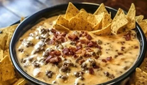 Sizzling bacon cheeseburger queso dip served in a bowl with tortilla chips