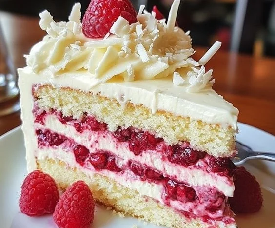 Slice of White Chocolate Raspberry Dream Cake with fresh raspberries.