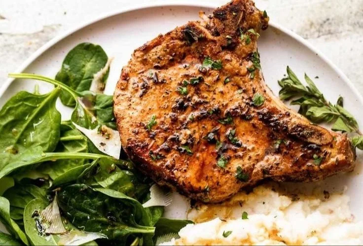 Oven baked bone-in pork chops served with herbs and spices
